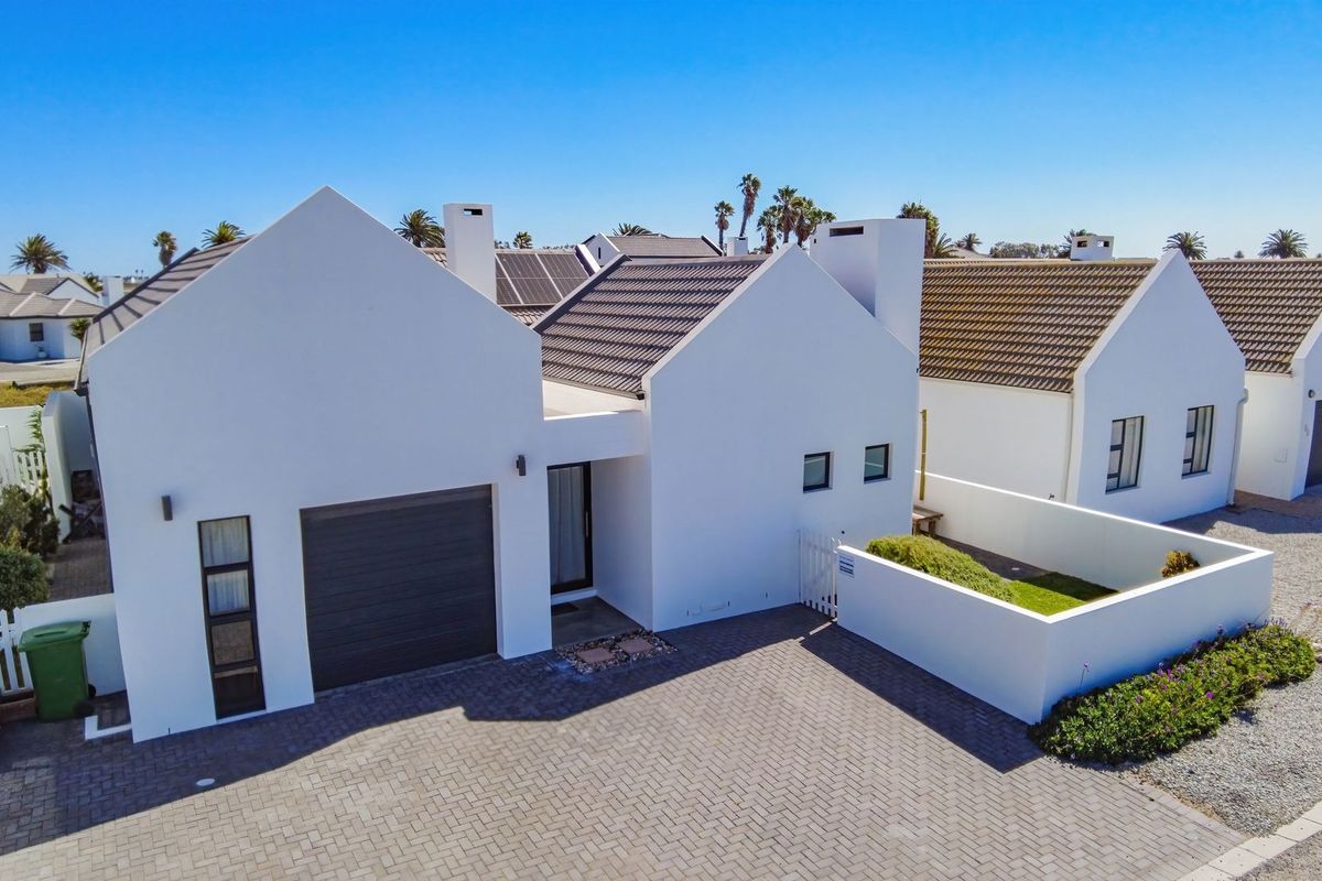 Aerial view of a modern residential property featuring a tiled roof, solar panels, paved driveway, and a secure garage.