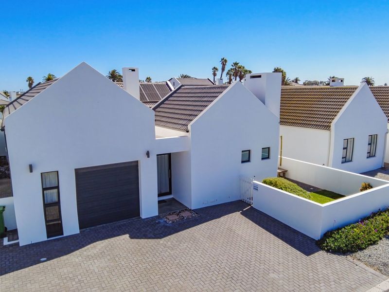 Aerial view of a modern residential property featuring a tiled roof, solar panels, paved driveway, and a secure garage.