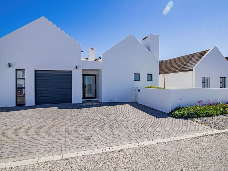 Modern front elevation of a house featuring a paved driveway, integrated garage, and clean white architectural lines.