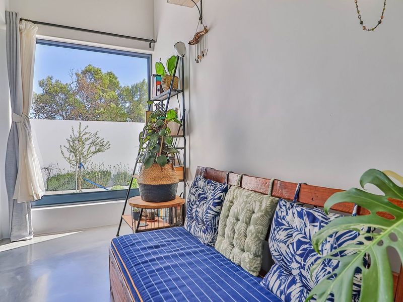A bright living area featuring polished concrete floors and a large picture window providing natural light and views of the garden.