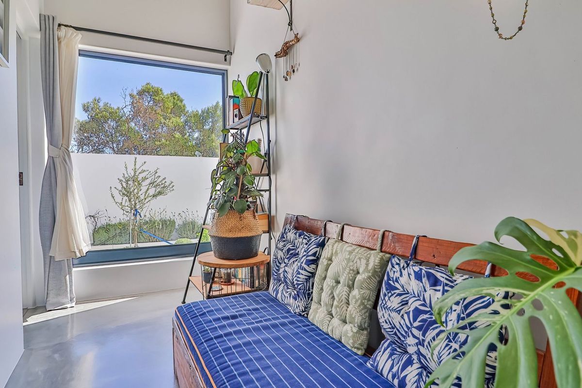 A bright living area featuring polished concrete floors and a large picture window providing natural light and views of the garden.