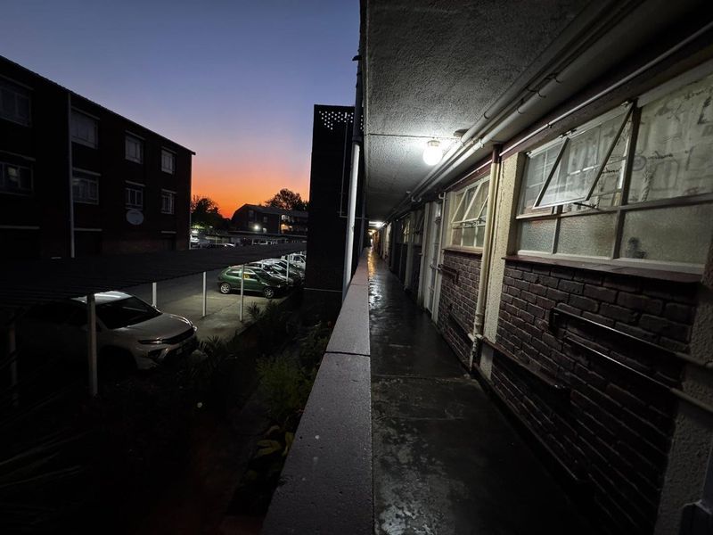 An exterior apartment walkway at dusk, featuring brick facade detailing and access to residential units.
