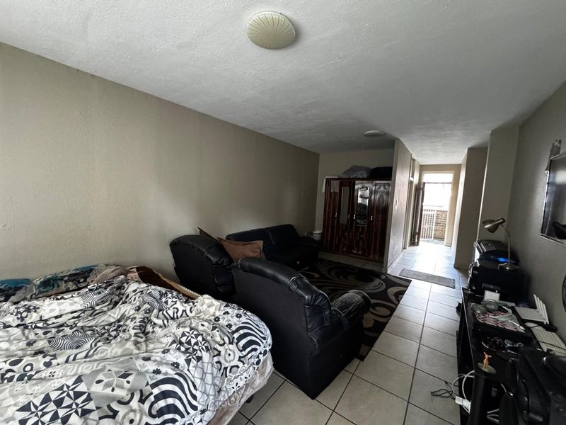 A bedroom featuring tiled flooring and ceiling lighting, with direct access to an exterior hallway area.