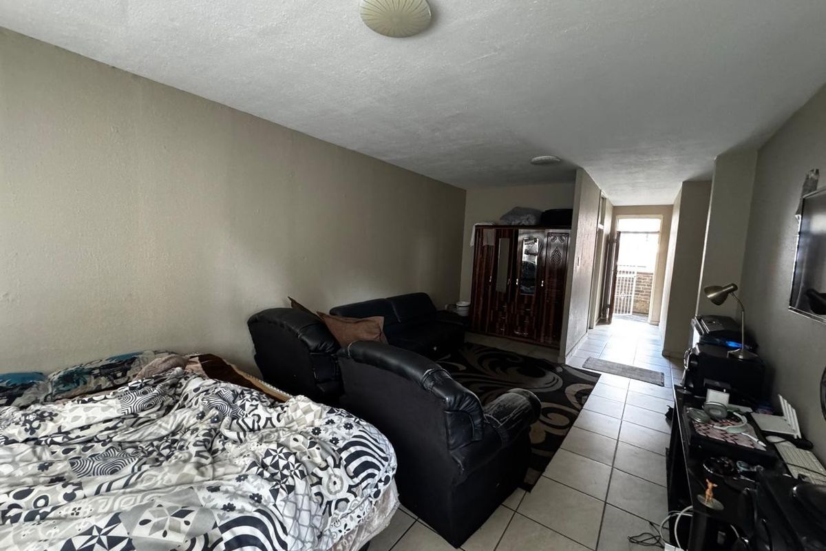 A bedroom featuring tiled flooring and ceiling lighting, with direct access to an exterior hallway area.