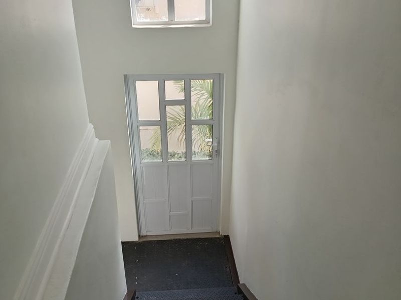 A functional stairwell featuring metal steps, a multi-pane glass door, and a matching window, providing access between levels in this commercial property.