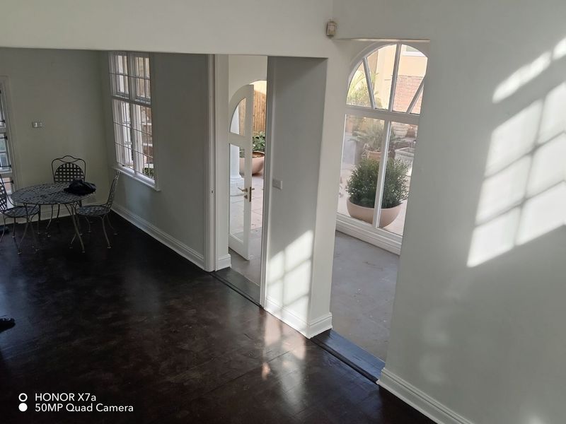 Bright living area featuring dark timber flooring, elegant arched windows, and direct access to an outdoor patio space.