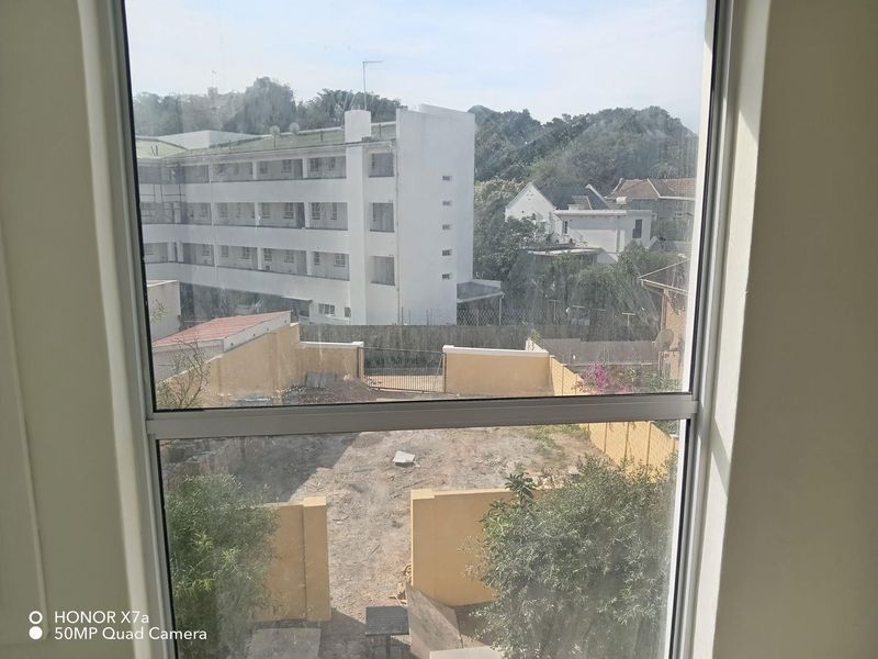A view from an interior window looking out over a rear yard area with perimeter walls and surrounding residential buildings.