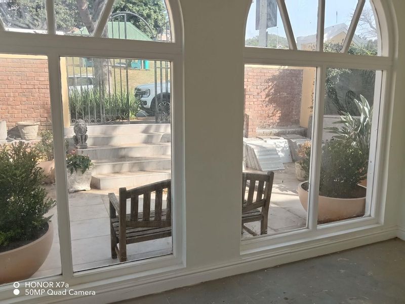 A bright, empty interior space featuring large arched windows that provide a clear view of the outdoor patio area.
