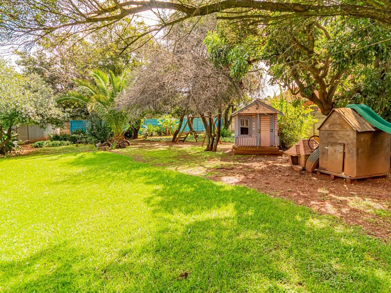 A spacious, well-established garden featuring mature trees, a lush lawn, and boundary fencing, providing a private outdoor setting.