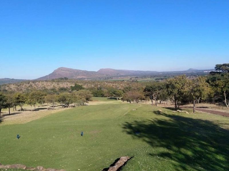 A scenic view overlooking a golf course with rolling hills and natural landscape in the background.