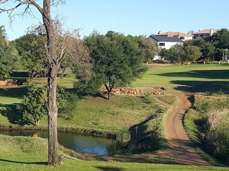 A scenic view overlooking a well-maintained golf course with a small water feature and lush green surroundings.