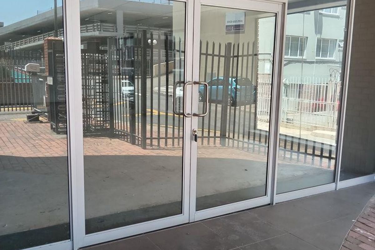 Commercial entrance featuring aluminium-framed glass double doors and large storefront windows with tiled flooring, providing clear visibility into the premises.