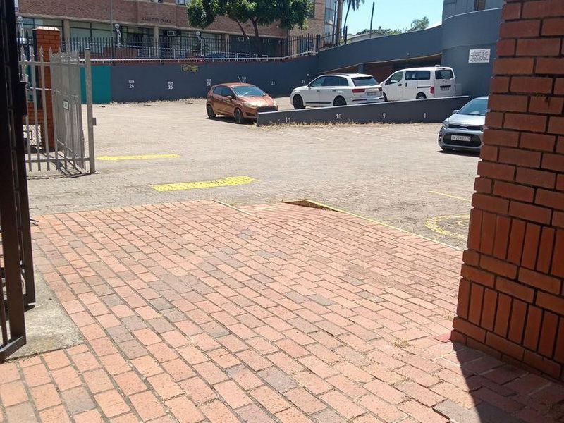 Commercial parking area featuring paved driveway access, brick retaining walls, and designated parking bays.