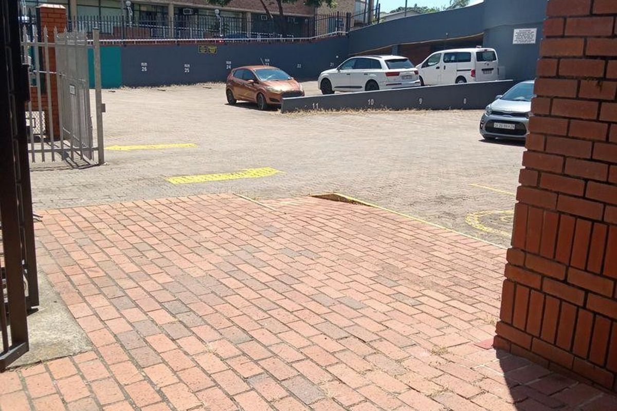 Commercial parking area featuring paved driveway access, brick retaining walls, and designated parking bays.