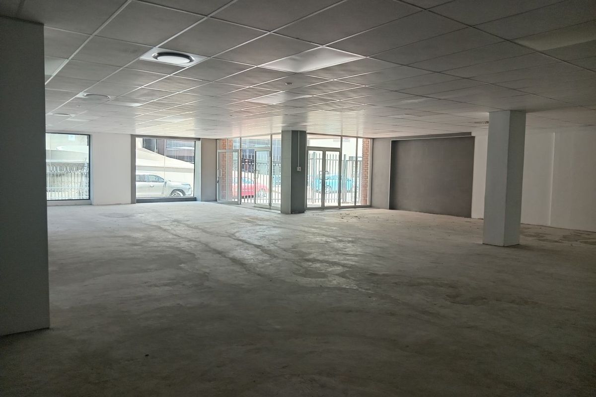 Spacious open-plan commercial unit featuring a suspended ceiling, recessed lighting, concrete flooring, and large glass storefront windows providing ample natural light.