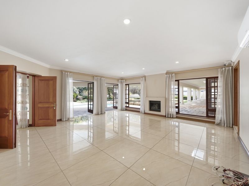 Spacious, light-filled living area featuring polished tile flooring, a built-in fireplace, and multiple glass doors providing seamless access to the outdoor patio and pool area.
