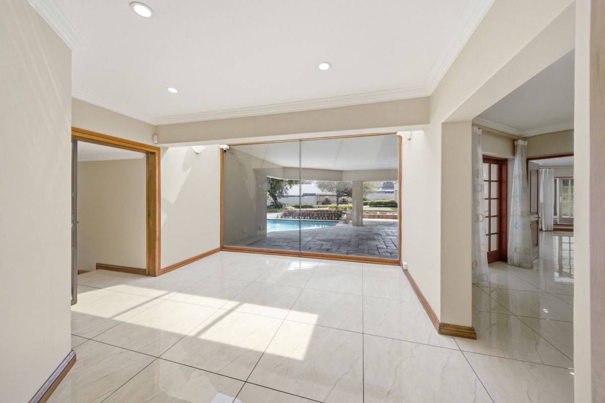 A bright, empty living area featuring large sliding glass doors that provide a seamless transition to the outdoor patio and pool area.