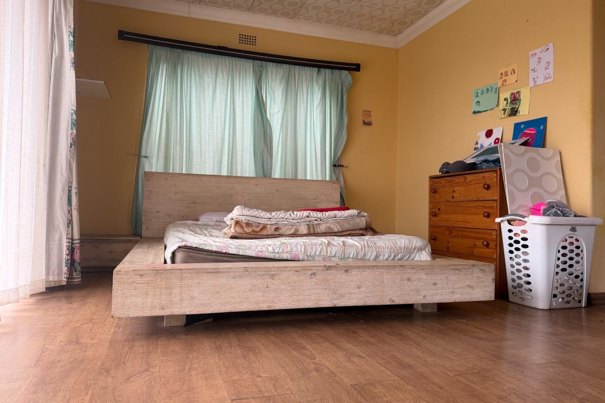 A bedroom featuring laminate flooring and patterned ceiling tiles, offering a functional space ready for cosmetic updates and modernization.