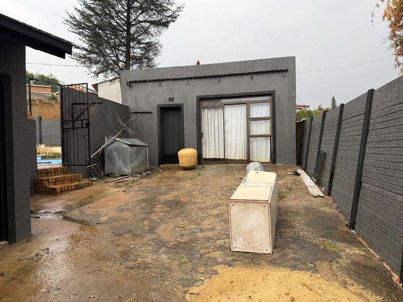 Rear exterior area featuring concrete paving, a sliding glass door, and perimeter walling, offering potential for landscaping or outdoor living space development.