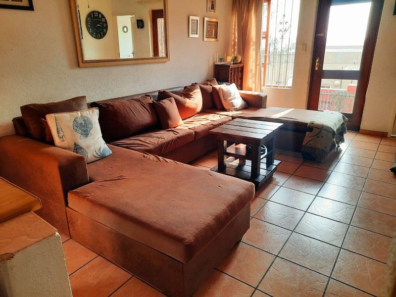 A comfortable living room featuring tiled flooring and direct access to an outdoor area through a glass panel door with security gate.