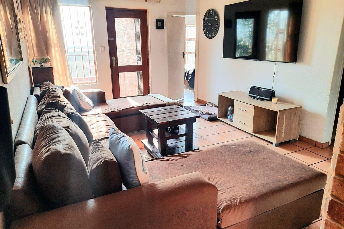 A living room featuring tiled flooring, a ceiling fan, and direct access to an exterior area through a secure door.