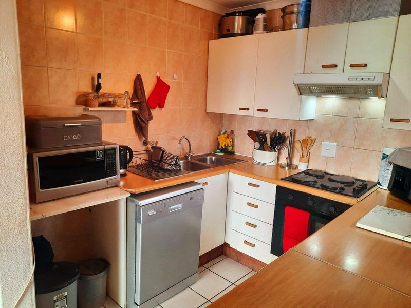 A compact kitchen featuring white cabinetry, laminate countertops, a tiled backsplash, and integrated cooking appliances including an oven and electric hob.