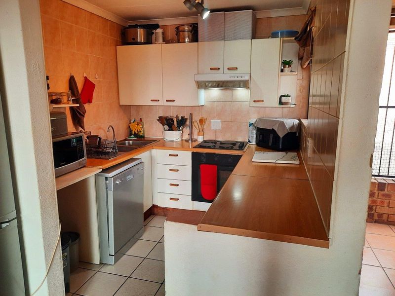 Compact kitchen featuring built-in cabinetry, laminate countertops, integrated oven and hob, and tiled finishes, offering a functional layout for daily meal preparation.