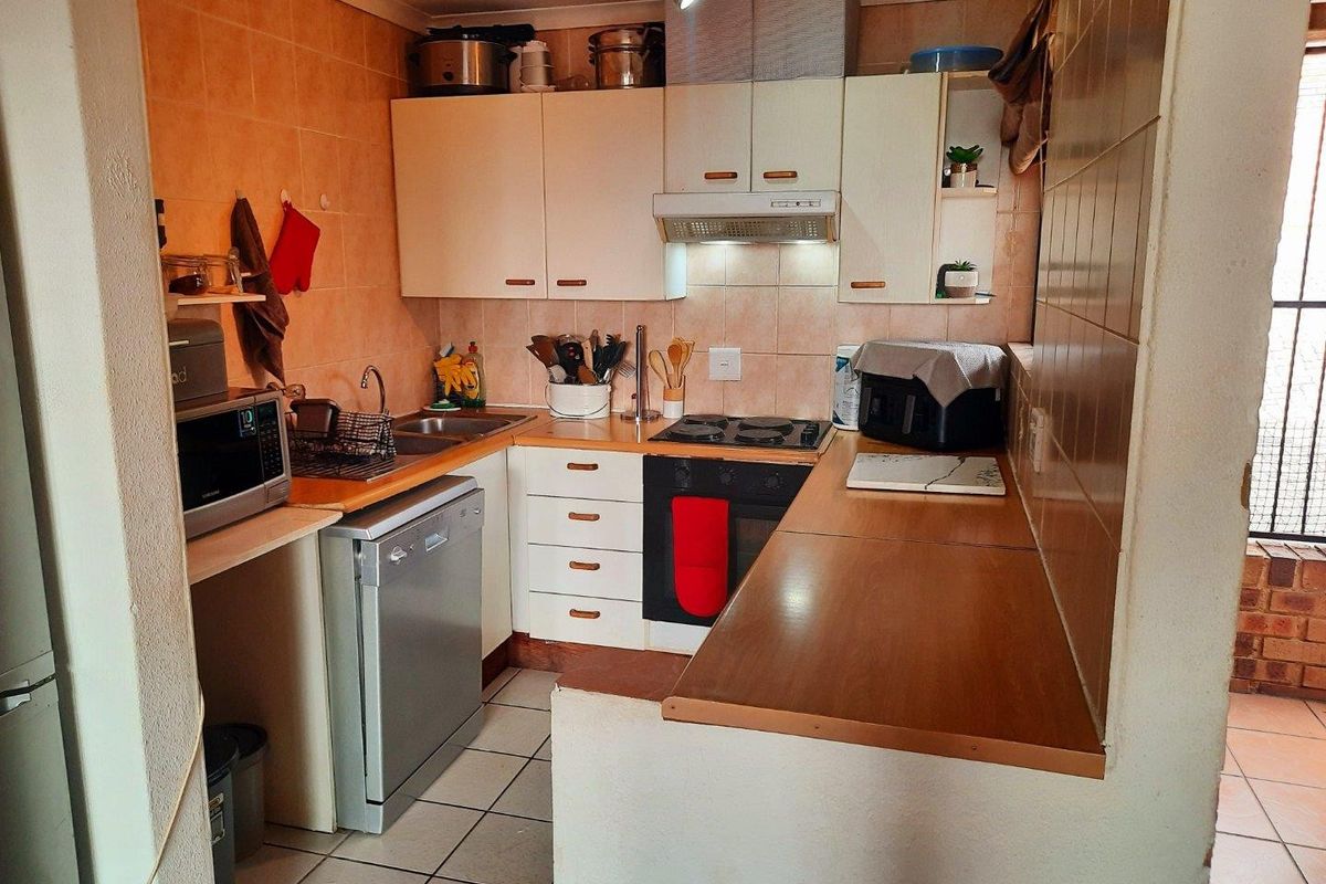 Compact kitchen featuring built-in cabinetry, laminate countertops, integrated oven and hob, and tiled finishes, offering a functional layout for daily meal preparation.