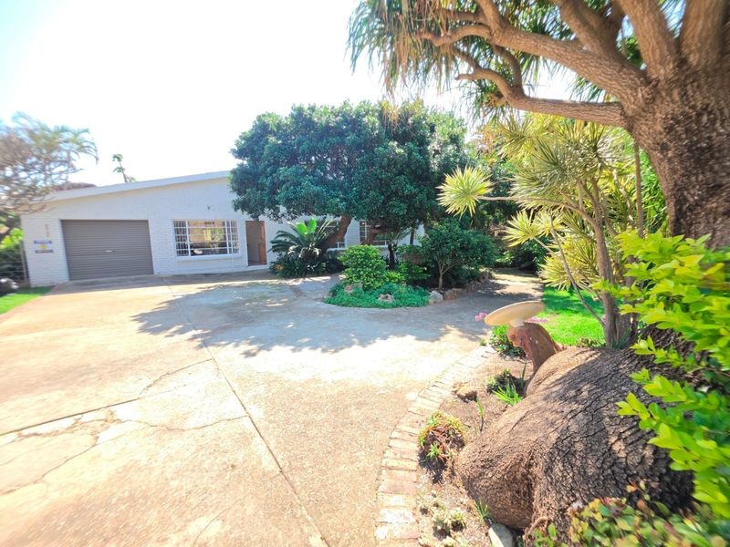 Front exterior view of the property featuring a concrete driveway, established garden, and a single garage door.