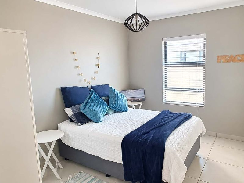 A well-maintained bedroom featuring neutral wall tones, tiled flooring, and a modern pendant light fixture, providing a clean and comfortable living space.
