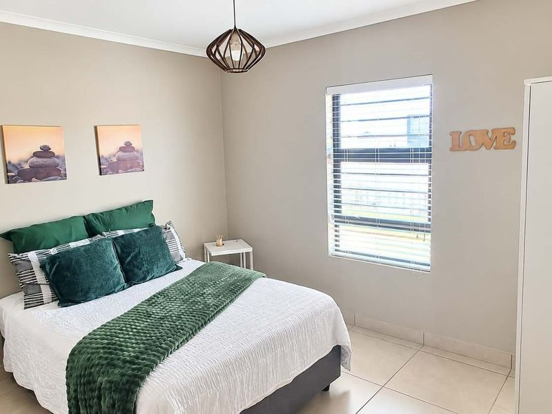 A well-maintained bedroom featuring neutral wall tones, tiled flooring, and a window fitted with horizontal blinds.