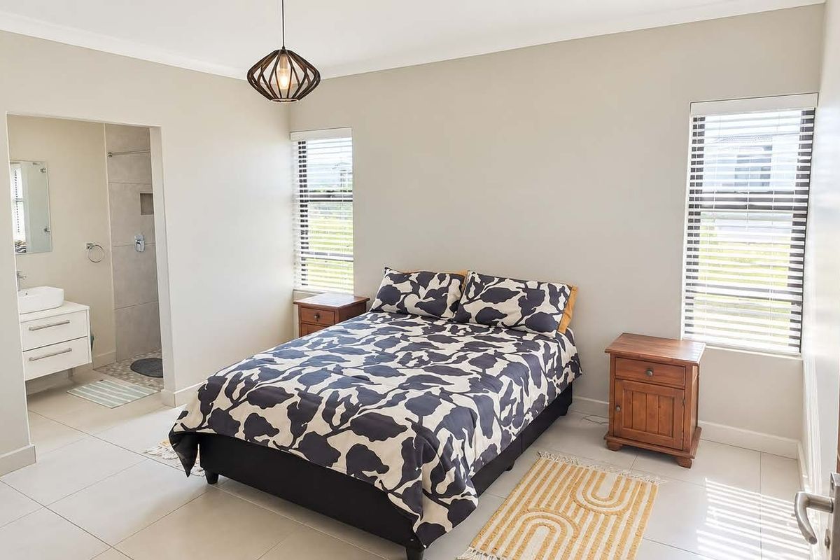 A well-maintained bedroom featuring tiled floors, neutral walls, and an adjoining en-suite bathroom with a modern vanity.