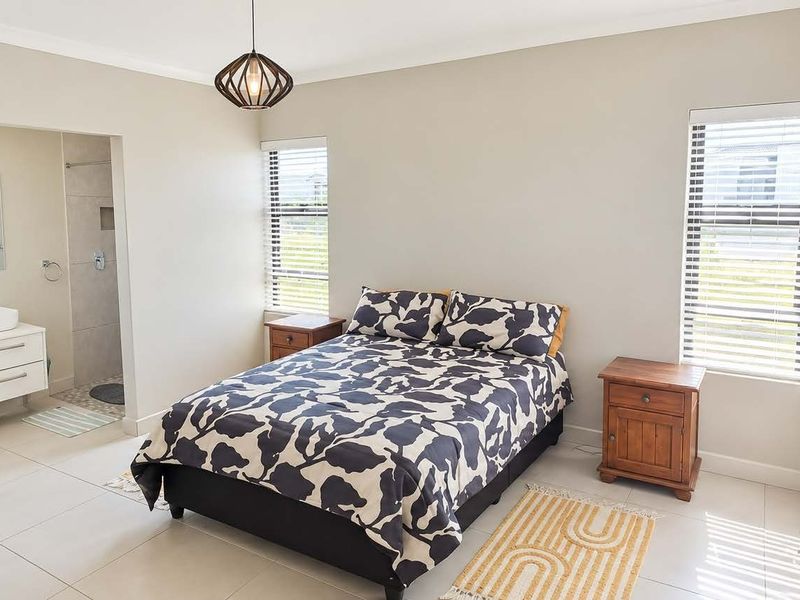 A well-maintained bedroom featuring tiled floors, neutral walls, and an adjoining en-suite bathroom with a modern vanity.