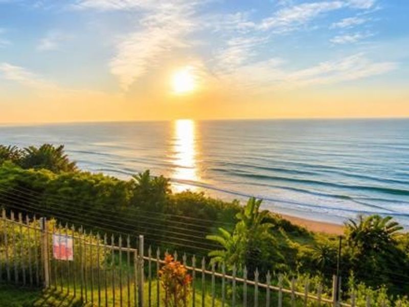 A scenic elevated view overlooking the ocean and coastline, featuring a secure metal perimeter fence with electric wiring.