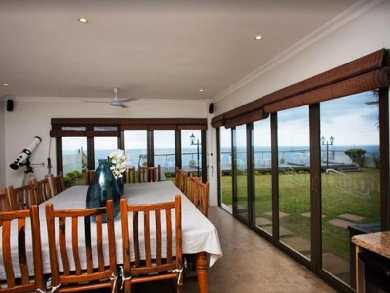 Spacious dining area featuring large sliding glass doors that provide seamless access to the garden and ocean views.