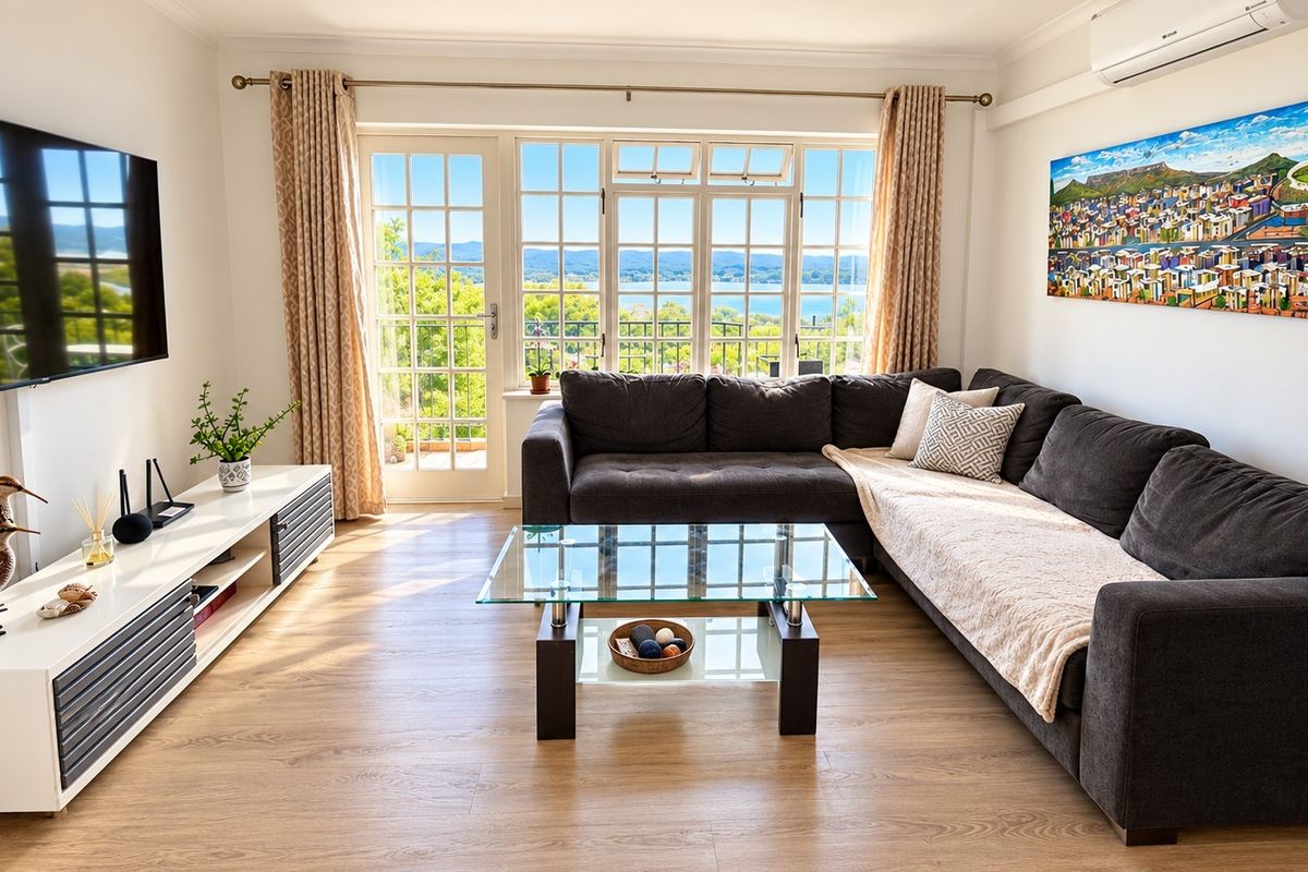 A bright and well-maintained living room featuring laminate flooring, a wall-mounted air conditioner, and large french doors offering scenic views.