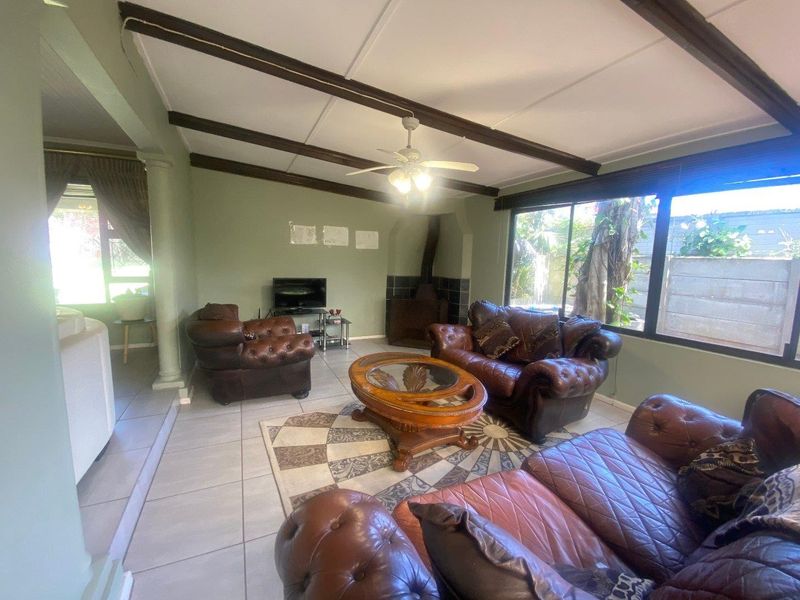 Spacious living room featuring exposed ceiling beams, a built-in fireplace, and large sliding glass doors that provide ample natural light.