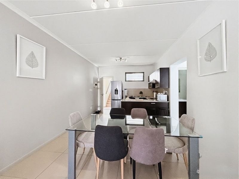 Open-plan living and dining area featuring tiled floors and a functional kitchen with built-in cabinetry and an extractor fan.