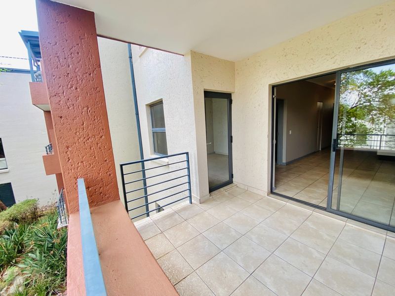 A covered balcony featuring tiled flooring, a metal balustrade, and sliding glass door access to the interior living space.