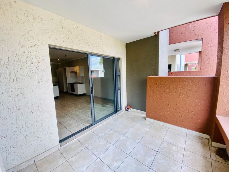 A covered balcony featuring tiled flooring and a sliding glass door providing access to the interior living area.