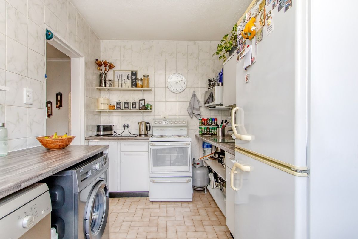 A functional kitchen featuring tiled walls and flooring, built-in cabinetry, and a freestanding oven, offering a practical layout for daily meal preparation.