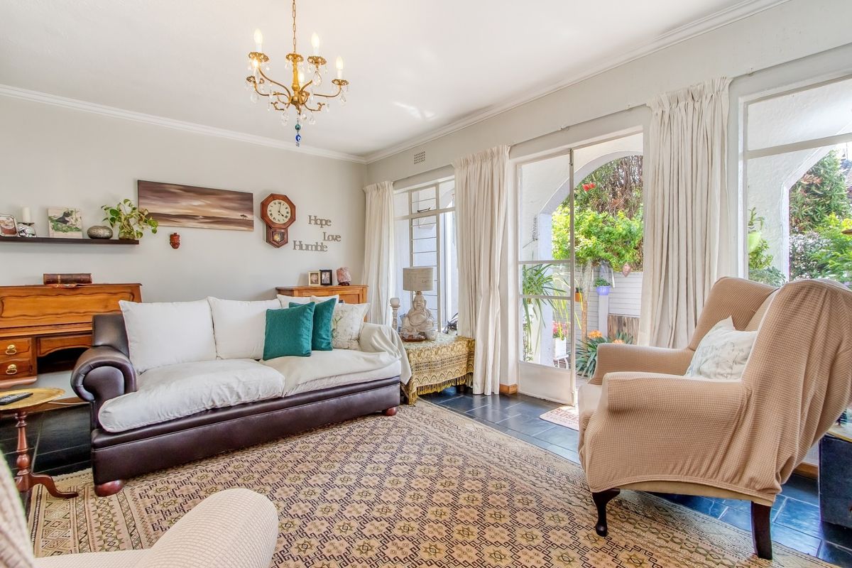 A bright living room featuring slate tile flooring, classic cove cornicing, and direct access to a private outdoor patio area through glass sliding doors.