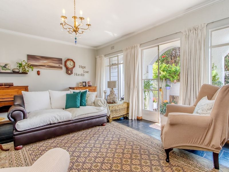 A bright living room featuring slate tile flooring, classic cove cornicing, and direct access to a private outdoor patio area through glass sliding doors.