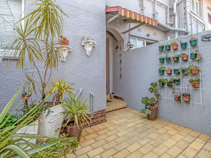 A private outdoor patio area featuring tiled flooring, textured walls, and a small overhead awning, providing a compact space for outdoor relaxation.