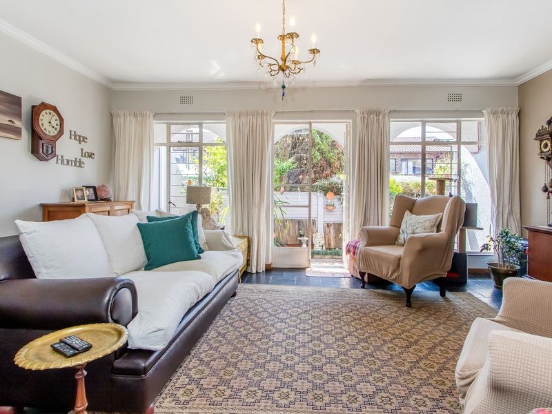 A bright living room featuring slate flooring, classic cornice detailing, and French doors providing direct access to the outdoor patio area.