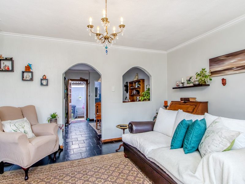 A cozy living room featuring classic archways, decorative coving, and a central chandelier, providing a warm and inviting atmosphere.