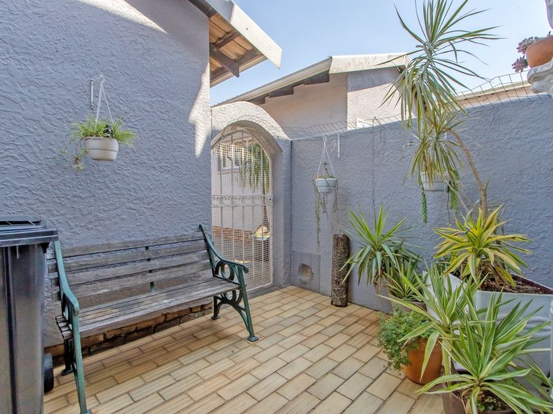 A private rear courtyard area featuring tiled flooring, textured walls, and a secure gated entrance.