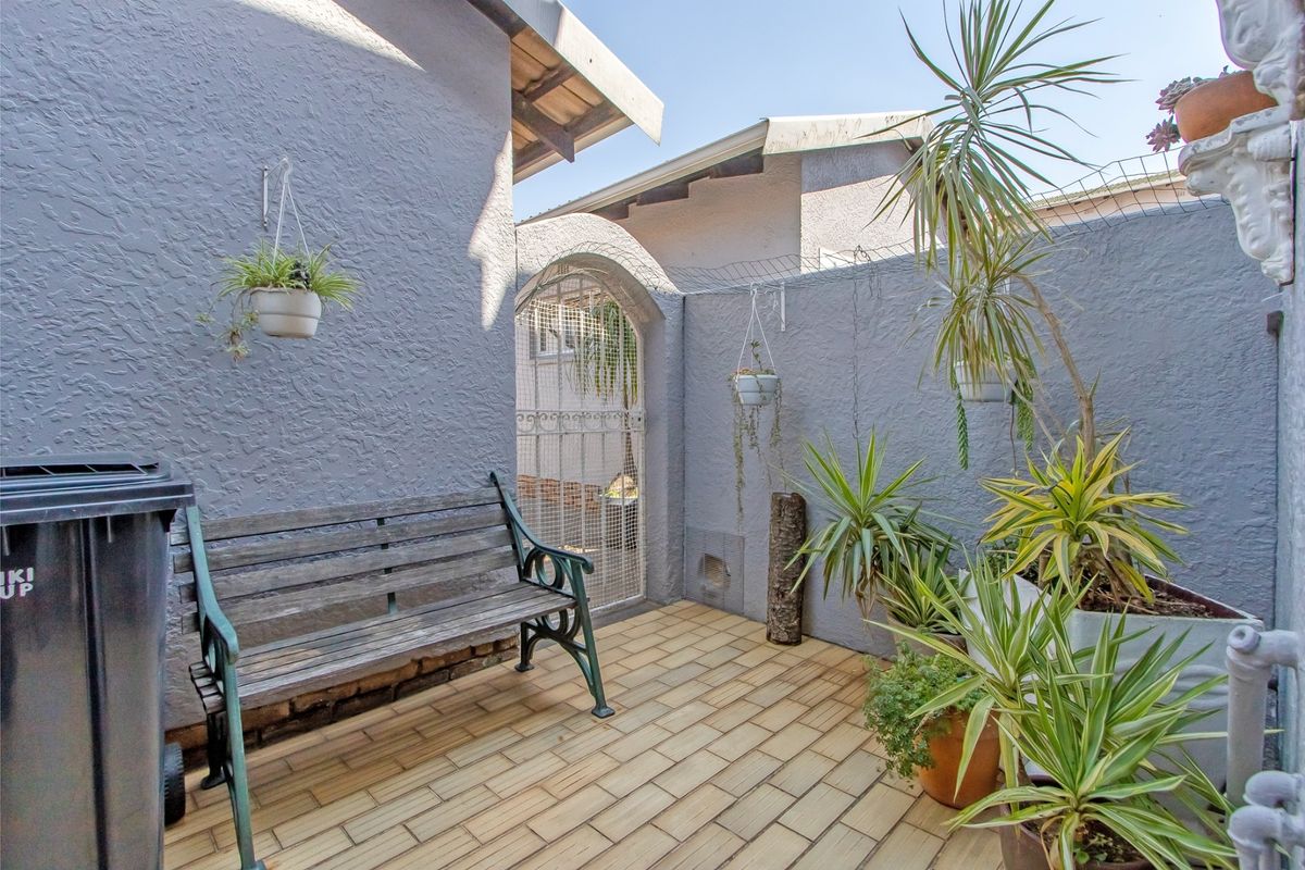 A private rear courtyard area featuring tiled flooring, textured walls, and a secure gated entrance.