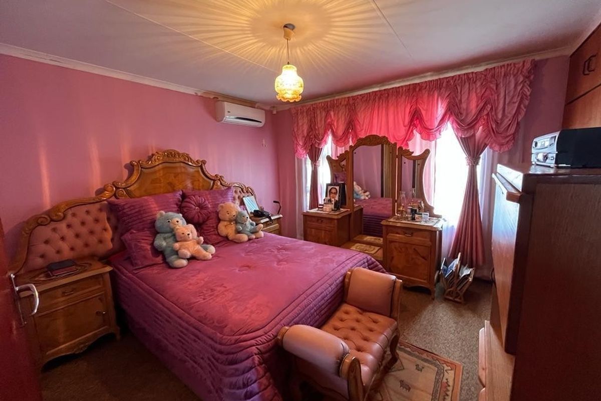 A bedroom featuring carpet flooring, a built-in wardrobe, and a wall-mounted air conditioning unit.