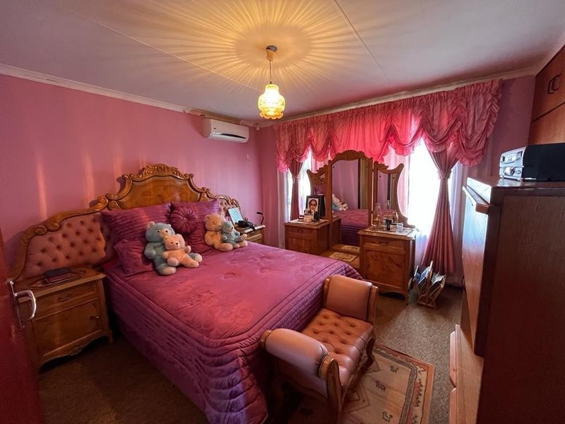 A bedroom featuring carpet flooring, a built-in wardrobe, and a wall-mounted air conditioning unit.